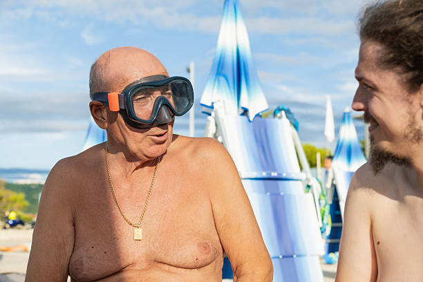 Elderly man asking his grandson how to use a diving mask