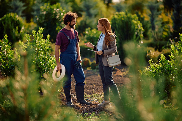 istock Happy worker and businesswoman communicating during quality control at tree nursery. 2233227053
