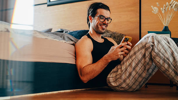 istock Smiling man using smartphone for online dating in bedroom 2233233418