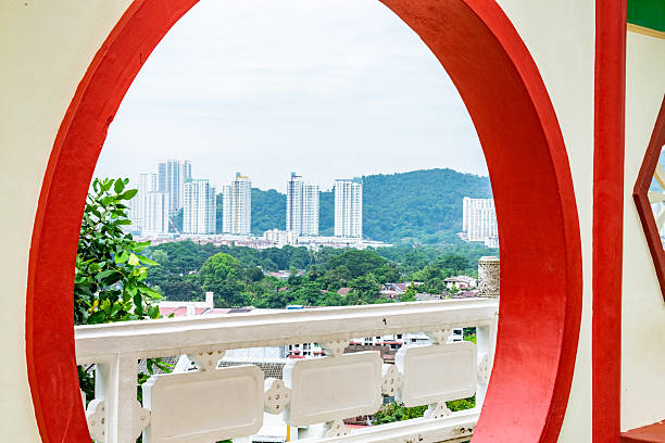 Modern cityscape of penang, malaysia, seen through a circular window of a traditional chinese temple