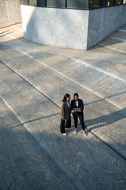 istock Businesswomen using digital tablet outside office building 2233239282