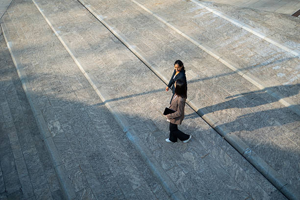 istock Two businesswomen walking and talking on modern urban steps 2233239290