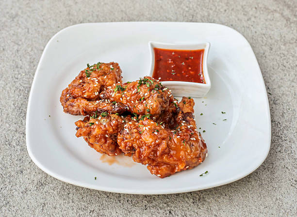 Honey glazed chicken wings with sesame seeds and Spicy dipping sauce in plate side view of fast food