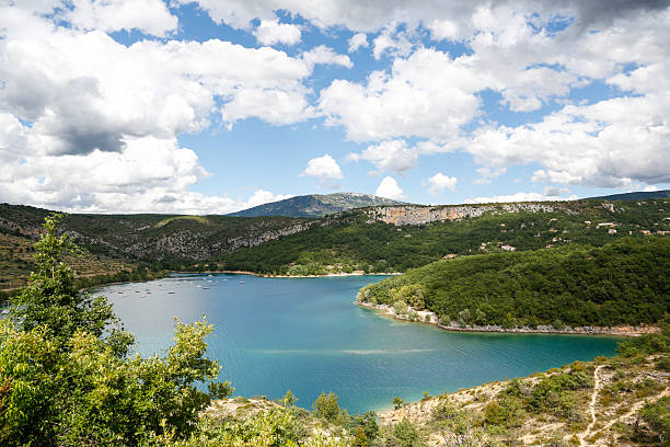 A picturesque view of a serene lake bordered by green hills and a dramatic sky.