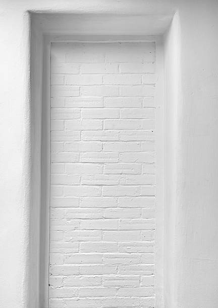 A white brick wall with an abstract recessed structure, presenting a minimal and modern aesthetic. This composition emphasizes clean lines, geometric patterns, and a serene monotone theme for sophisticated visual designs.