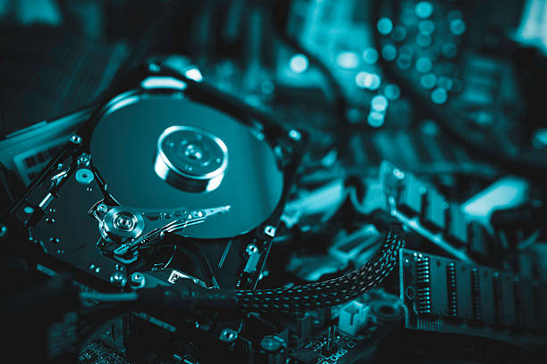 A close-up view of an open computer hard drive surrounded by electronic components and cabling, emphasizing technology.