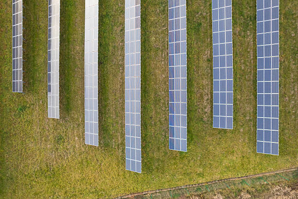 istock Top view of solar panels arranged in rows on green grass field 2233246547