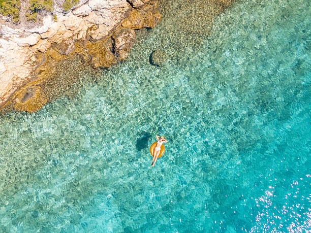 istock Woman Floating on Inflatable Near Rocky Shore 2233247346