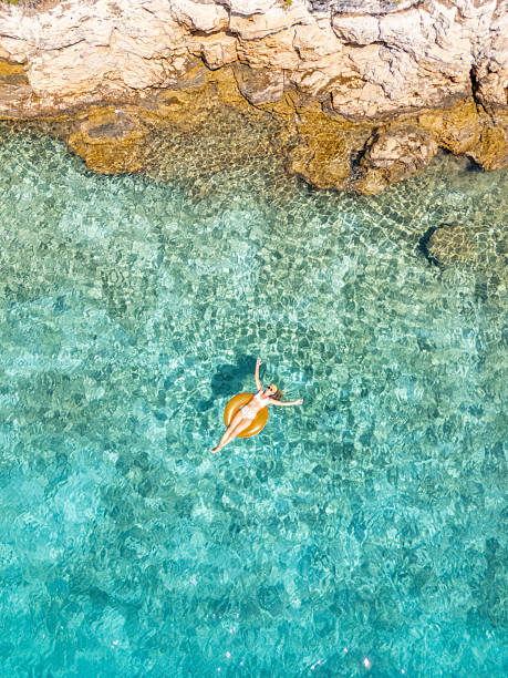 istock Woman Floating on Inflatable Near Rocky Shore 2233247514
