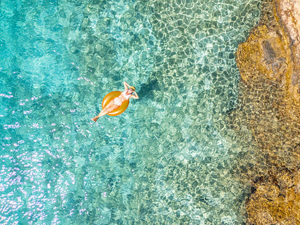 istock Woman Floating on Inflatable Near Rocky Shore 2233247876