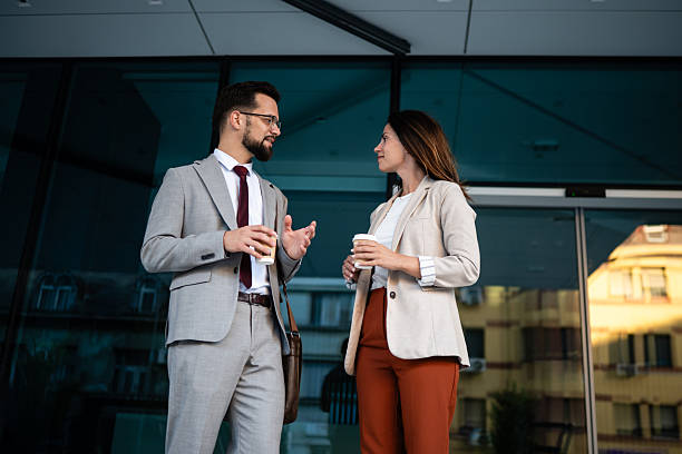 istock Businesspeople talking and holding disposable coffee cups outside office building 2233249987