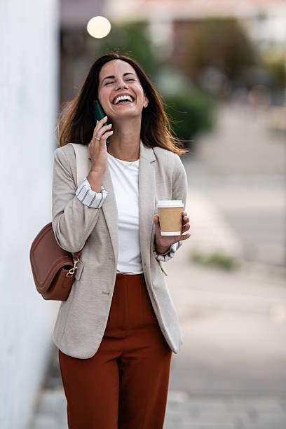 istock Happy businesswoman walking and talking on phone while holding coffee 2233250013