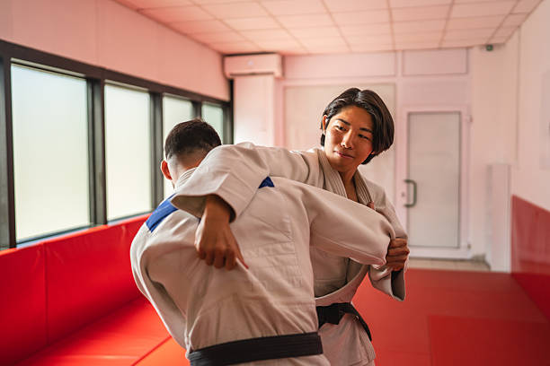 istock Determined female judo athlete performing a throw on male opponent during training 2233250047