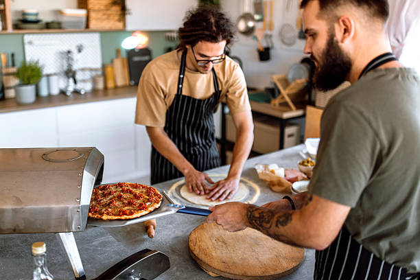 istock Two friends having fun, making pizza in domestic kitchen. 2233250227