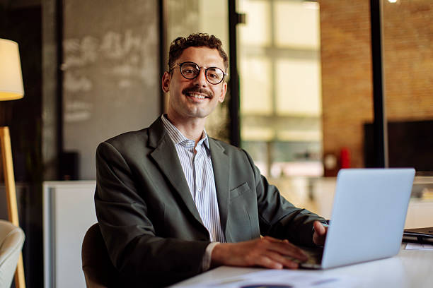 istock Confident Business Professional Smiling While Working in a Modern Office Environment On a Laptop 2233252446