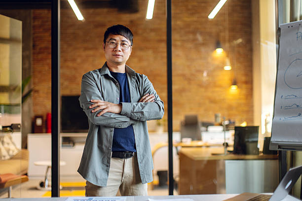 istock Confident Businessman Standing in Modern Office Space with Folded Arms 2233252474