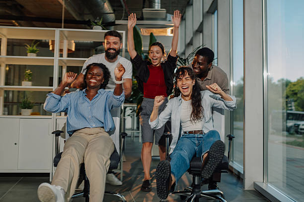 istock Excited business team having fun racing on office chairs 2233257799