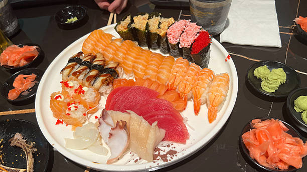 Assorted sushi platter featuring colorful rolls, fresh sashimi, and garnishes, beautifully arranged on a round white plate for culinary delight