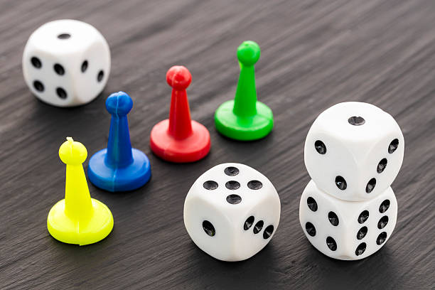 istock Colored game pieces and four white dice with black dots on a dark background 2233260320