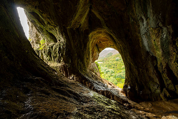 Scenic mountain view from the Thor's Cave entrance. Limestone cave, forest and white clouds. Peak District, Staffordshire, England, UK