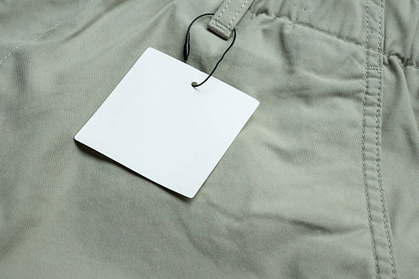 istock Blank white clothes tag label on gray fabric texture background 2233261668