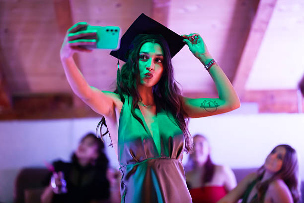 istock Young woman taking a selfie in graduation cap during celebration 2233261829