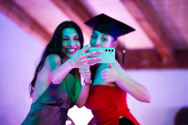 istock Graduates taking a celebratory selfie at a party in vibrant lighting 2233261834