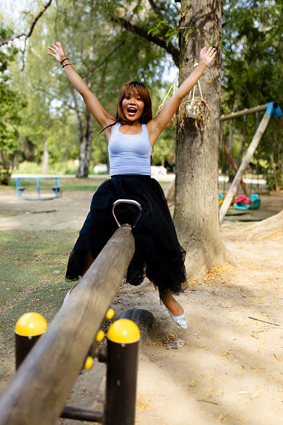 A little beautiful girl in a flat T-shirt and a plaid shirt enjoys playing in the autumn park. The concept of children's happiness in nature. A bright explosion of colors. Focus on the center of the carousel