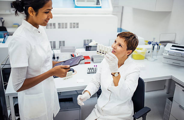 Mid Adult Caucasian and Young Indian Female Scientists Analyzing Samples in a Bright Laboratory