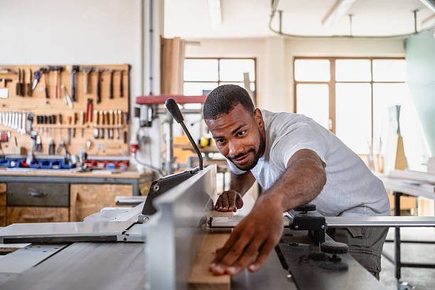 istock Skilled Multiracial Male Carpenter Operating Woodworking Machine in Bright Workshop 2233262410