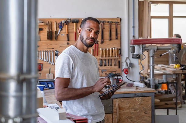 istock Professional Craftsman Examining Wood Project in Workshop with Tool Wall Background 2233262421