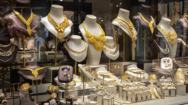 istock storefront window featuring a rich collection of gold jewelry on display. The display includes large, intricate necklaces on busts, as well as a variety of rings and other accessories 2233262566