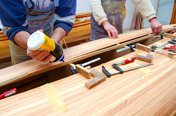 Young carpenters making canoe of their own design in their carpenter workshop.