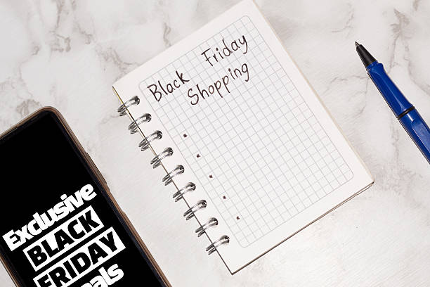 istock Blank Black Friday shopping list in a notebook with a pen and cell phone. Shopping planning, e-commerce, and deals 2233268975