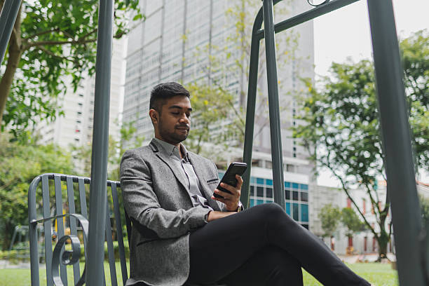 istock Asian office executive relaxes on a swing and uses a phone during lunch break 2233277508