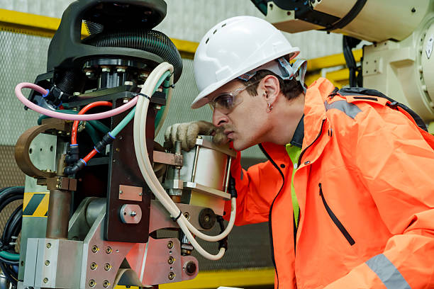 istock Caucasian male technician inspecting robotic machinery closely during automation system maintenance training in advanced factory environment wearing safety uniform and helmet 2233277895