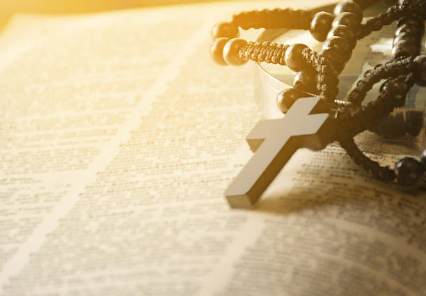 Wooden cross placed on opened page book, soft focus, concept for bible study of christanity priests.