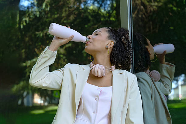 Young businesswoman drinking from a reusable bottle during her break in a park