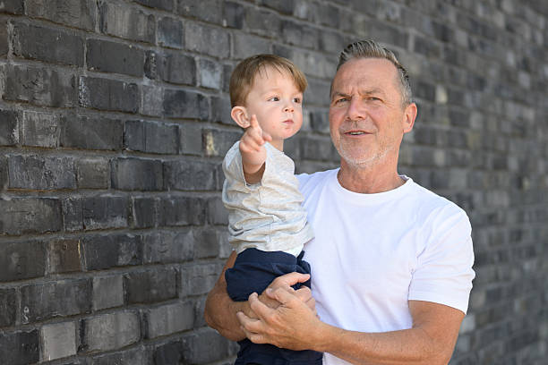 Baby boy looking over father's shoulder while daddy holding him, outdoor