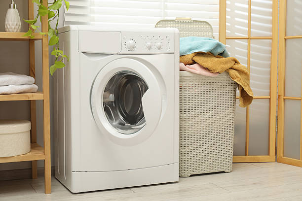 istock Wicker basket full of laundry and washing machine in bathroom 2233285172