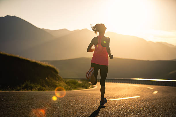 Woman runner running in sunset mountain road