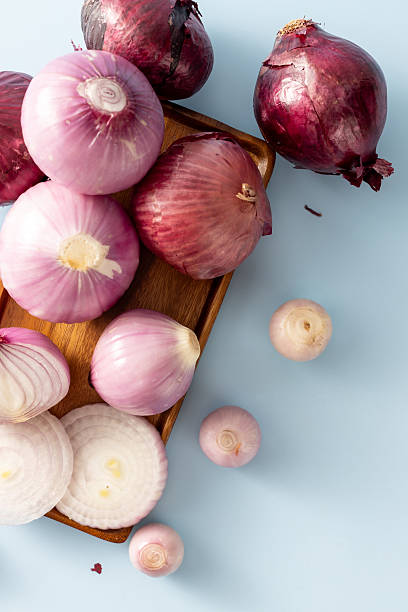 istock Fresh Red Onions on Wooden Tray with Sliced Pieces on Blue Surface 2233287515