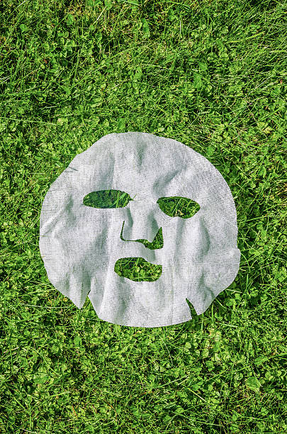 Skincare concept with a white sheet mask placed on natural green grass background. Great for beauty, wellness, and self-care themes. High quality photo