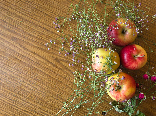 Freshly picked apples and gypsophila flowers create a charming still life composition on a rustic wooden table, evoking a sense of autumnal abundance and natural beauty