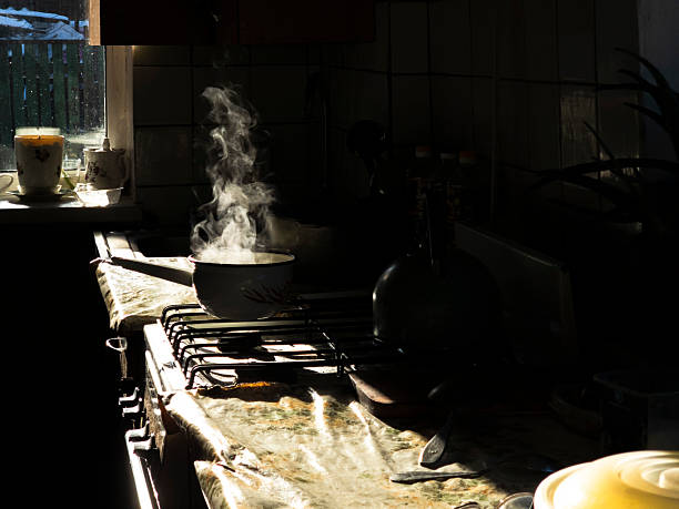 istock Steaming pot on stovetop, morning sunlight casting shadows across worn kitchen, illuminating dusty countertop and porcelain vessels near window 2233292134