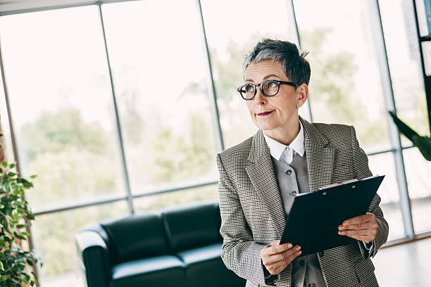 istock Confident professional woman holding a clipboard in a bright modern office space dressed elegantly in formalwear 2233292416