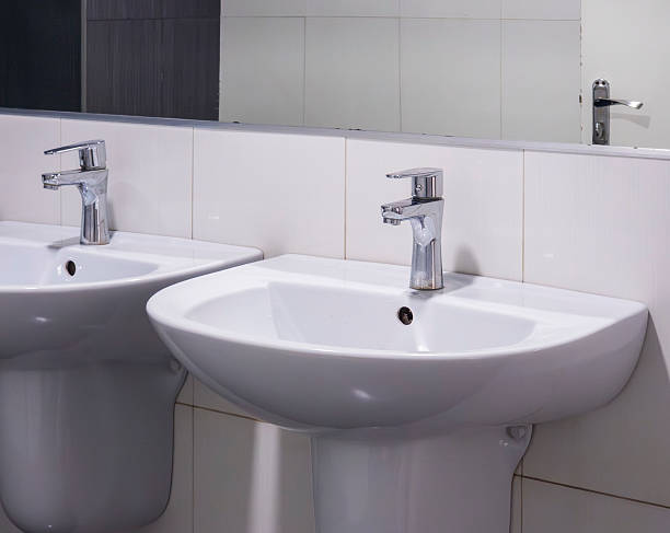 istock White ceramic sinks flanking sleek chrome faucets, reflecting contemporary bathroom design in polished mirror backdrop, highlighting clean minimalist aesthetic 2233292692