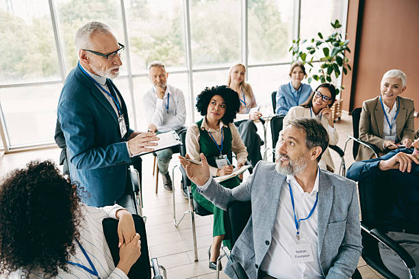 Diverse group of professionals collaborating during a business meeting indoors, exchanging ideas and fostering teamwork. Vibrant environment with individuals in formal attire signifies collaboration and productivity in a modern workspace.