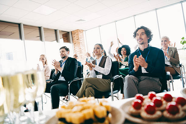 istock Diverse group of professionals clapping during a conference in a bright office setting. Plates of refreshments enhance 2233293286