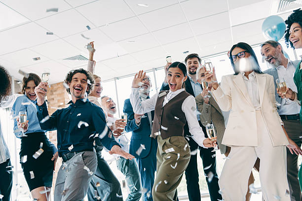 istock Group of professionals in an office celebrating a successful project with confetti and champagne raising the glasses 2233293351